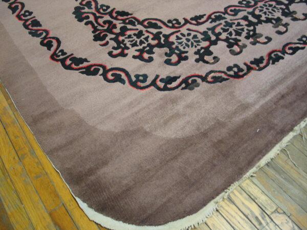 Mauve and brown shaded rug displaying dark blue and red scrolling patterns rests on yellow wood planks.