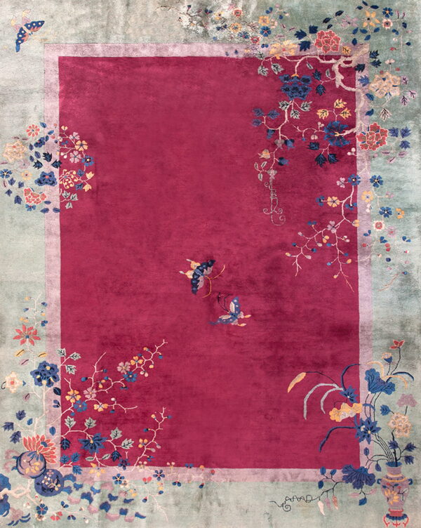 Plush magenta rug with an icy green border and colorful floral and butterfly patterns.