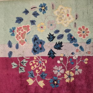 Floral patterned rug with a medium pile on horizontal bands of light green, pale gray, and deep magenta.