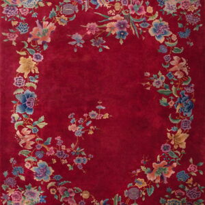 Deep red rug featuring a multicolored floral garland and vases around a solid oval field.