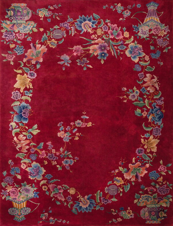 Deep red rug featuring a multicolored floral garland and vases around a solid oval field.