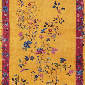 Yellow rug featuring a spreading vine pattern with blue flowers and a detailed red border with vase motifs.