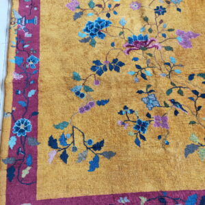 Golden rug with multicolored vine and bird motifs, detailed by a wide magenta pictorial border.