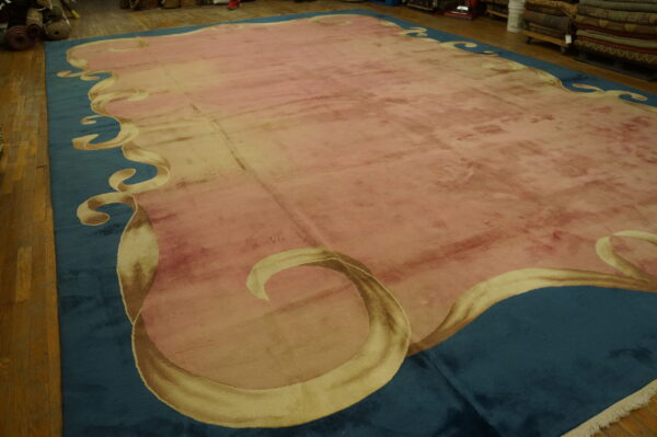 A large plush pink rug with a teal ribbon border is displayed on wide plank wood flooring.