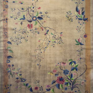 A muted beige and gray rug with high sheen displays a colorful, intricate floral and bird pattern.