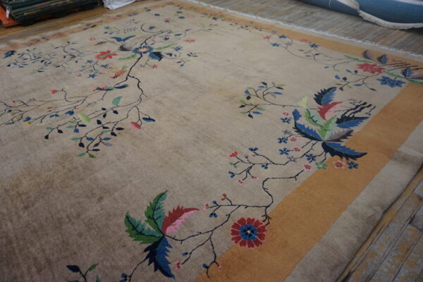 Low-pile beige rug displaying a detailed colorful floral and bird pattern with a wide gold border.