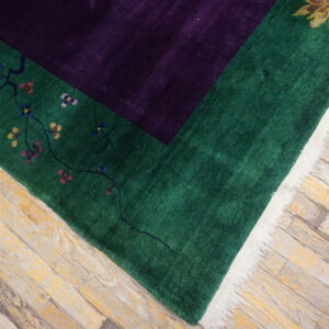 Deep purple field and green border rug featuring colorful florals, visible on worn wood plank flooring.