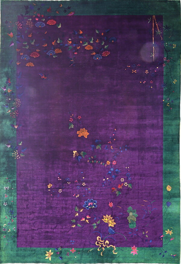 Deep purple rug with scattered floral motifs, multicolored accents, and a wide green border.