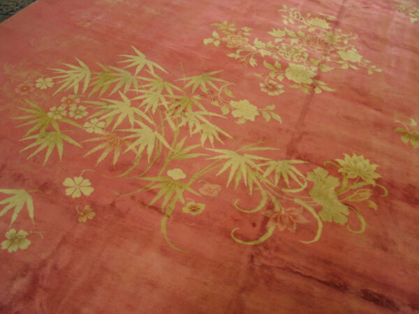 Pink distressed rug featuring light green floral clusters and large bamboo-like leaves.