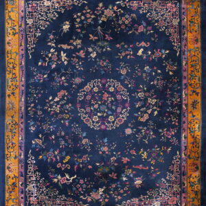 Navy blue rug featuring scattered colorful floral motifs and a detailed gold and purple border.