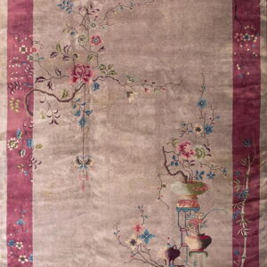 Grayish-taupe rug with asymmetrical floral motifs, a vase and stand, and a wide magenta border.