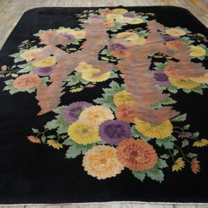 Black high-pile rug with colorful floral motifs and an abstract brown central design on plank wood floors.