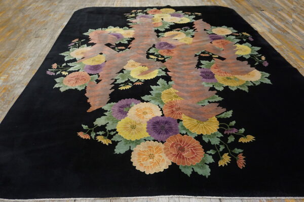 Black high-pile rug with colorful floral motifs and an abstract brown central design on plank wood floors.
