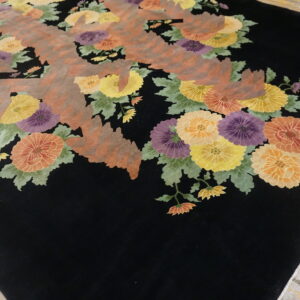 Black rug featuring colorful floral clusters and abstract reddish-brown geometric shapes on wood floor.