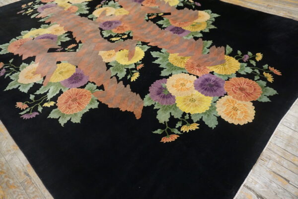 Black rug featuring colorful floral clusters and abstract reddish-brown geometric shapes on wood floor.