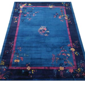 Vibrant blue traditional rug with wide navy borders showcases intricate floral designs in pink, yellow, and blue.