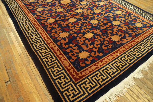 Navy blue, gold, and rust patterned rug with geometric borders rests on rustic light wood floors.