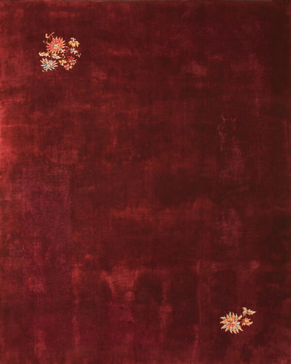 Deep red rug with a mottled field texture and scattered multicolored floral motifs.