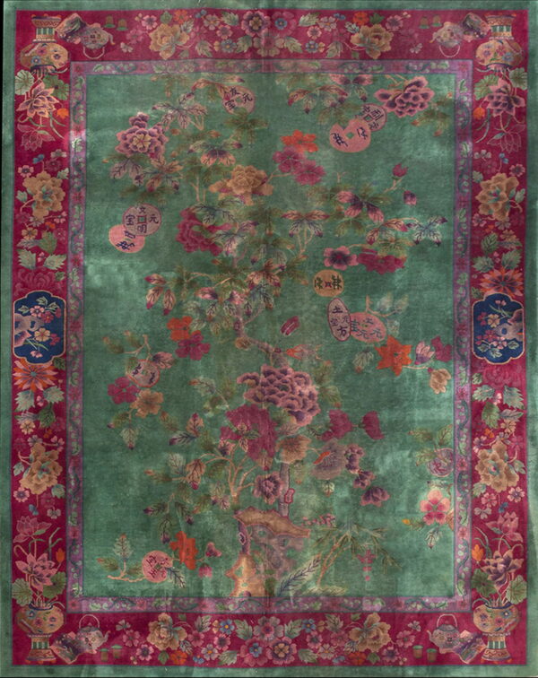 Deep green rug with an ornate central tree pattern and a wide magenta border featuring flowers and vases.