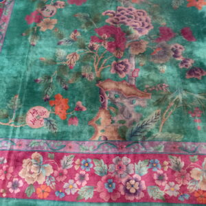 Plush rug featuring a teal center with purple and tan florals and a wide magenta border design.