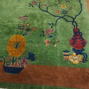 Green rug with colorful flowers, vases, and an orange medallion, framed by a wide brown border.