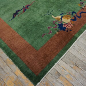 Plush green rug featuring a wide rust border and multicolored floral motifs sits on distressed wood planks.