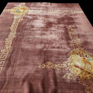 Deep pink rug with textured high pile and carved gold meander and cloud border details.