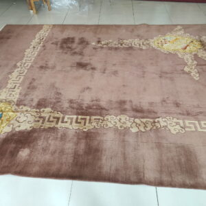 High pile dusty rose rug with a beige Greek key and cloud motif border on white tile.