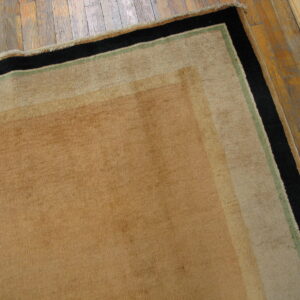 Tan area rug featuring broad black and thin green borders on rustic wood flooring.