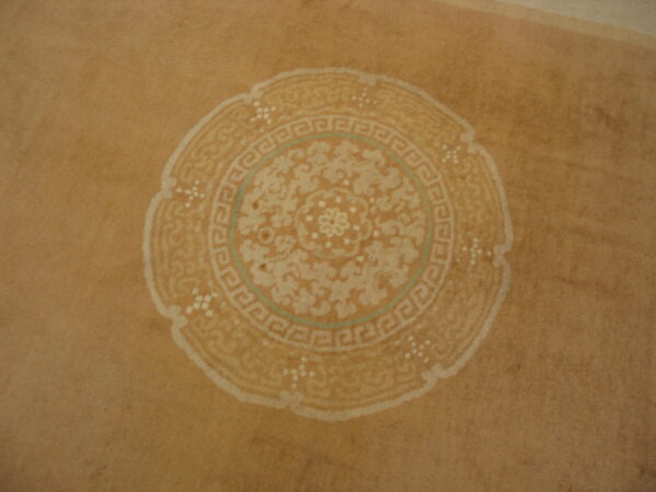 Tan rug featuring a faded round medallion with cream floral and greek key patterns, accented by teal.