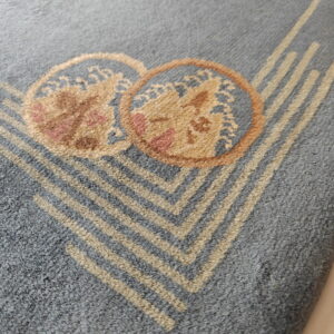 Detailed view of a gray rug with tan chevron stripes and overlapping floral medallions.