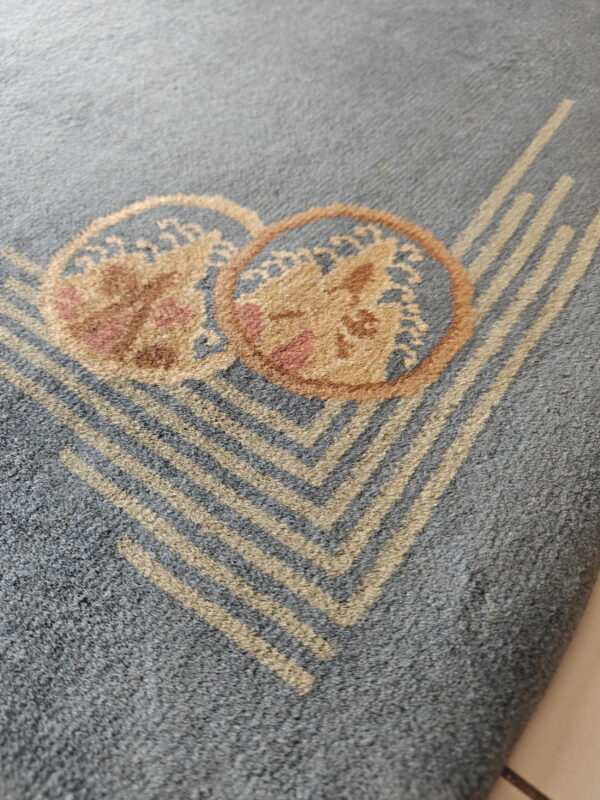 Detailed view of a gray rug with tan chevron stripes and overlapping floral medallions.
