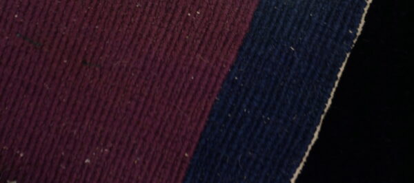 Detail view of a ribbed textile featuring deep maroon and navy blue color blocks.