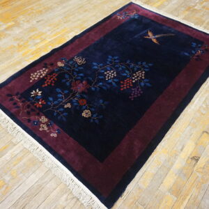 Navy blue rug with a burgundy border features floral and bird motifs on distressed wood planks.