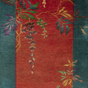 Teal and red rug with a sculpted pile and a botanical pattern of colorful vines, leaves, and a bird.