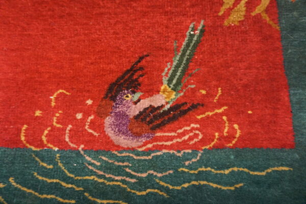 Detail of a medium-pile rug featuring a purple and black waterfowl motif on a red field with green and yellow waves.