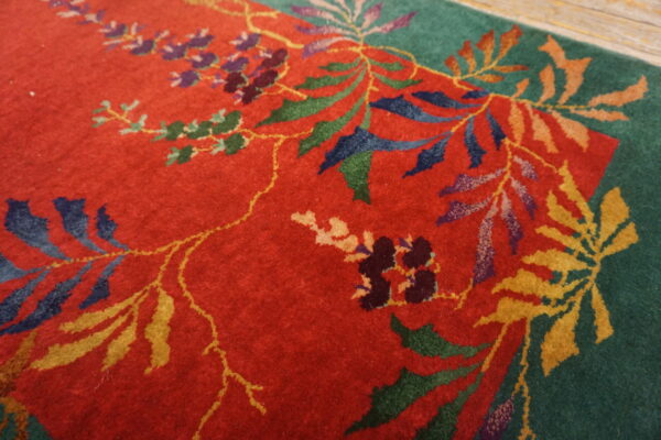 The red and green rug with multi-colored floral patterns rests on light wood flooring.