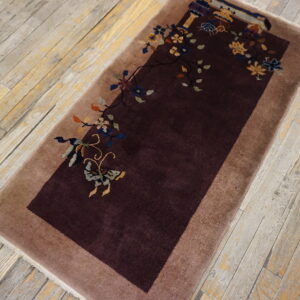Dark maroon rug with a tan border features asymmetric floral and butterfly patterns on distressed wood planks.