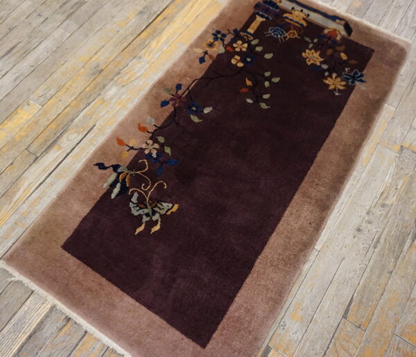 Dark maroon rug with a tan border features asymmetric floral and butterfly patterns on distressed wood planks.