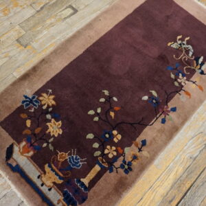 A deep maroon runner with a colorful floral pattern and tan border lies on distressed wood floors.