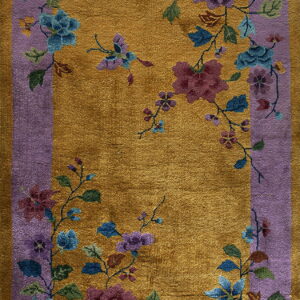 Golden yellow high pile rug featuring a dense blue and purple floral pattern inside a lavender border.