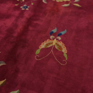 Deep red rug featuring a central multicolored butterfly surrounded by stylized blue and green flowers.