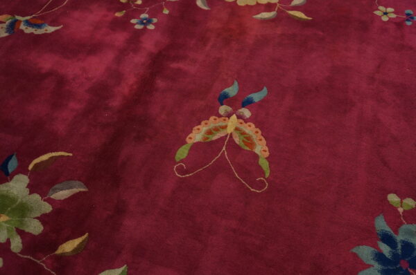 Deep red rug featuring a central multicolored butterfly surrounded by stylized blue and green flowers.