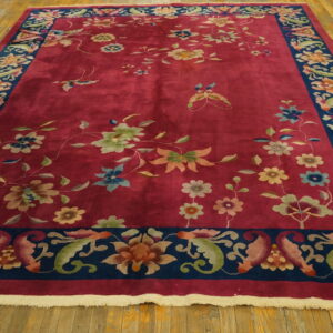 High pile crimson rug with colorful flowers and butterflies, framed by a wide navy blue floral border.
