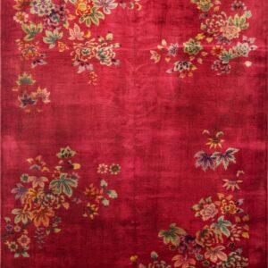 Close view of a vibrant red rug featuring large floral motifs in pale green, tan, and purple on a plush pile.