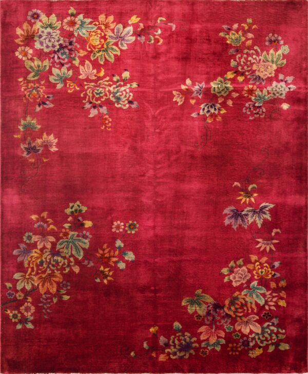 Close view of a vibrant red rug featuring large floral motifs in pale green, tan, and purple on a plush pile.