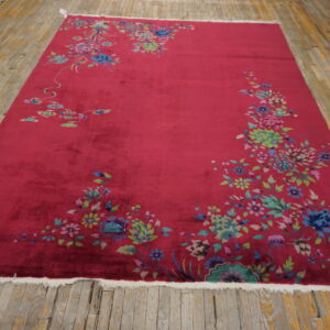Bright magenta rug featuring sprawling multicolored floral designs lies on worn yellow wood flooring.