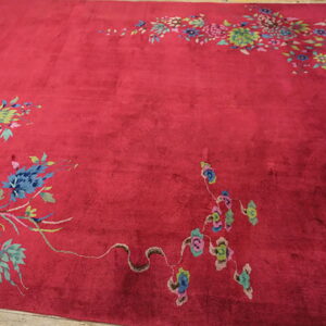 Plush red rug featuring brightly colored floral bouquets and vines on exposed wood planks.