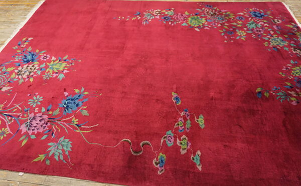 Plush red rug featuring brightly colored floral bouquets and vines on exposed wood planks.