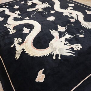 Plush black rug displaying intricate ivory and pale pink dragon and cloud patterns on wood flooring.